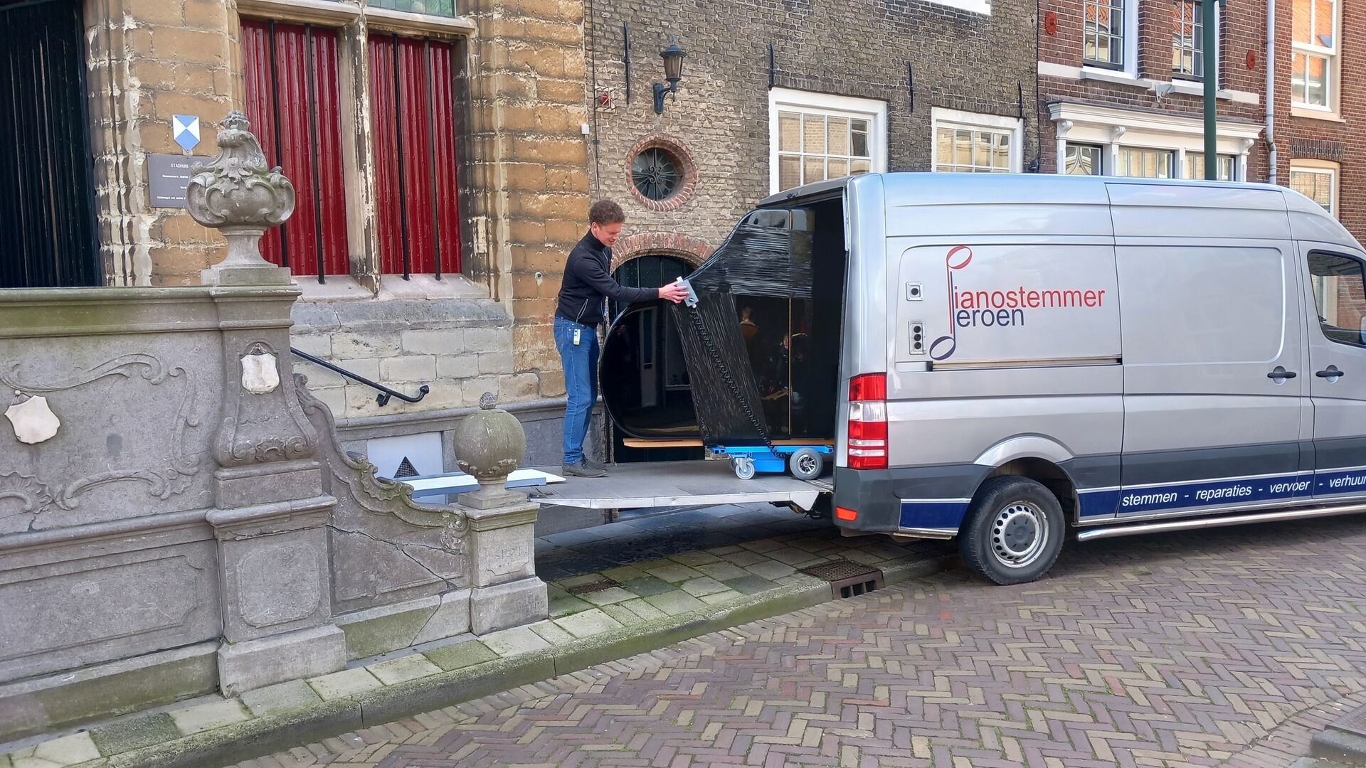 Bus met pianolift bij een kerk